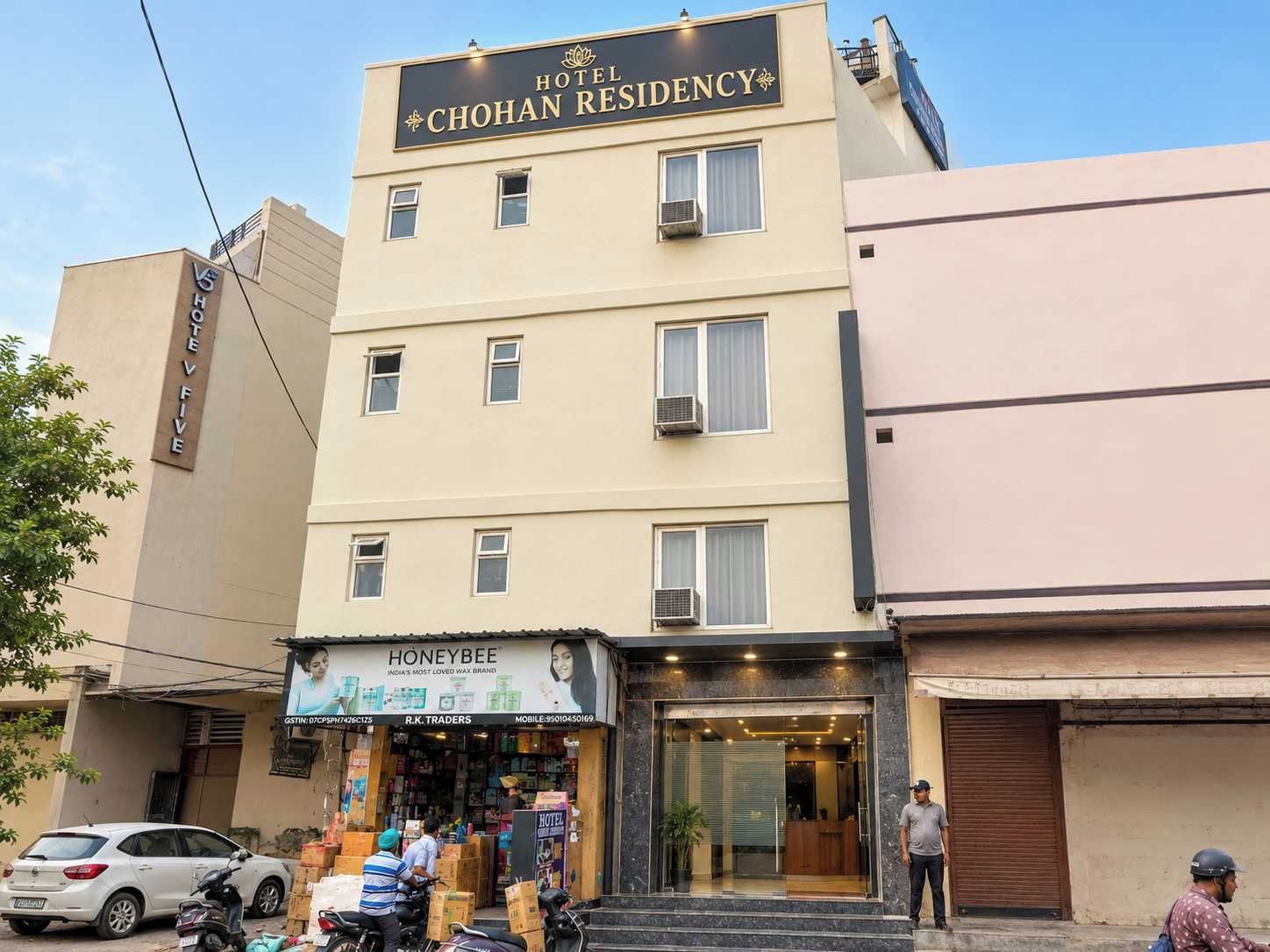 Ett hotell som heter ”Hotel Chohan Residency” med en butiksfasad för ”Honeybee” framför ingången.