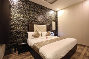 A hotel room with a large bed, a headboard, a nightstand, and a wall with a patterned wallpaper. - Hotel O CSJS International (Amritsar)