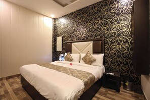 A hotel room with a large bed, a nightstand, a lamp, and a wall with a decorative pattern. - Hotel O CSJS International (Amritsar)