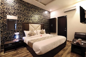 A hotel room with a bed, bedside tables, a mirror, a wardrobe, and an air conditioning unit. - Hotel O CSJS International (Amritsar)