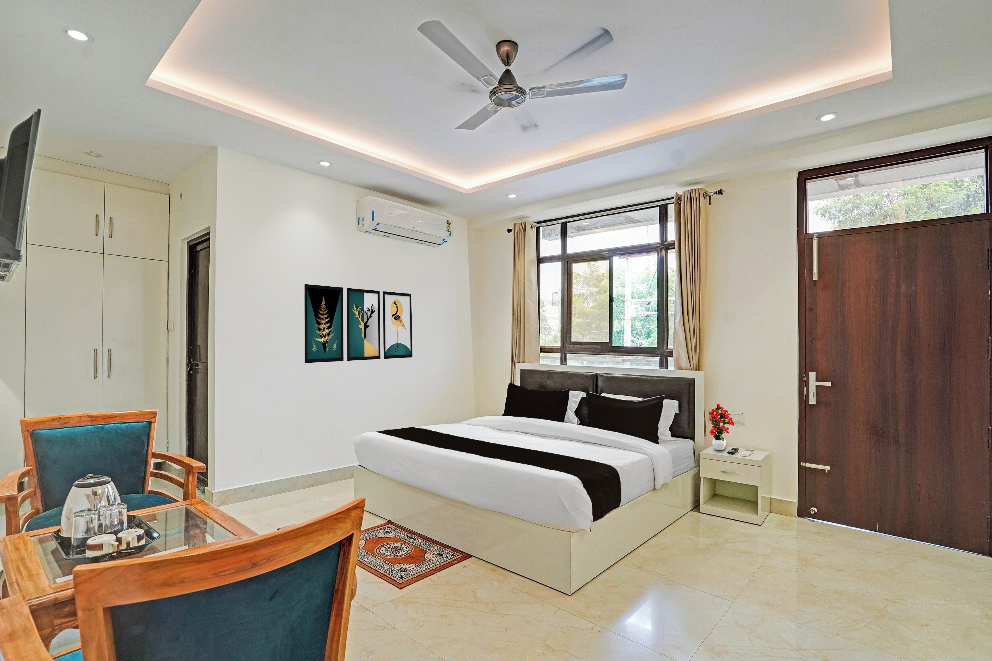 A hotel room with a bed, a desk, a chair, a window, and a ceiling fan.