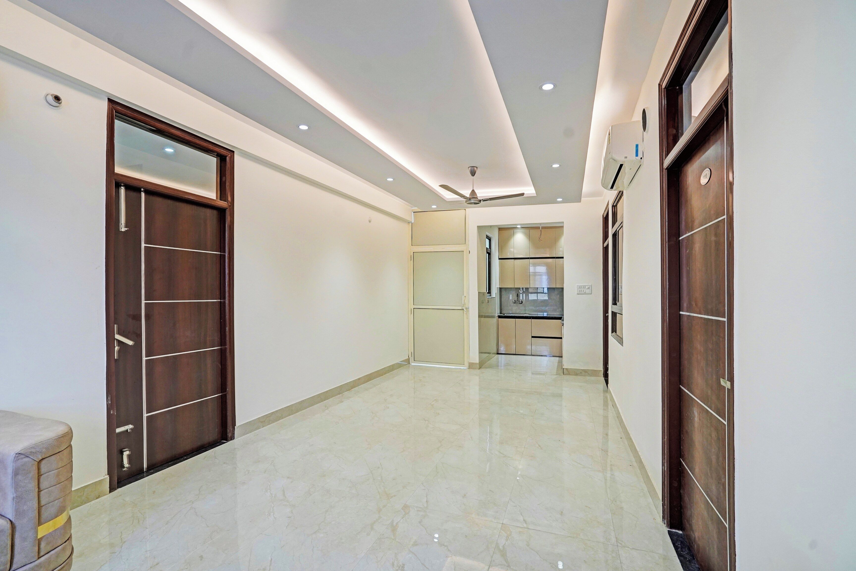 A corridor with a tiled floor, wooden doors, and recessed ceiling lighting.