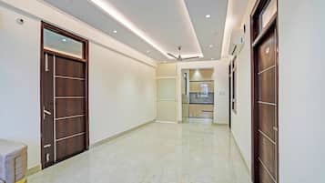 A corridor with a tiled floor, wooden doors, and recessed ceiling lighting.
