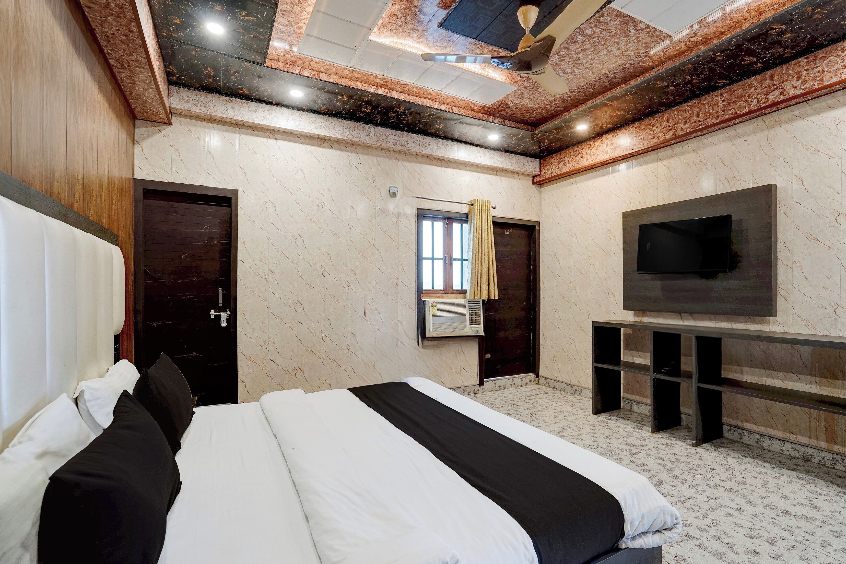 Habitación de hotel con una cama grande, un televisor de pantalla plana y un techo con diseño decorativo.