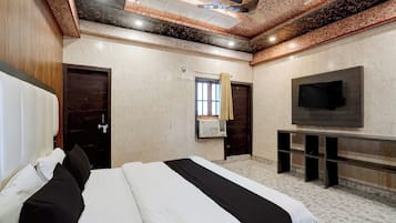 Habitación de hotel con una cama grande, un televisor de pantalla plana y un techo con diseño decorativo.