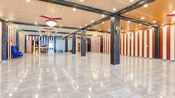 Un vestíbulo amplio con piso de mármol pulido, techos altos con vigas a la vista y una escalera central.