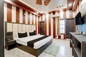 A hotel room with a large bed, a bedside table, a TV, and a wardrobe. - Hotel O Aurivique hotels and Banquets (Lucknow)