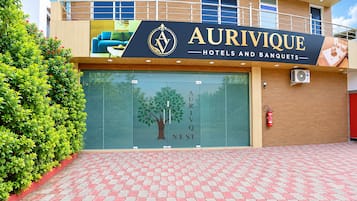 Entrada de un hotel con un letrero que dice 'AURIVIQUE HOTELS AND BANQUETS' y un gráfico de árbol en la puerta.