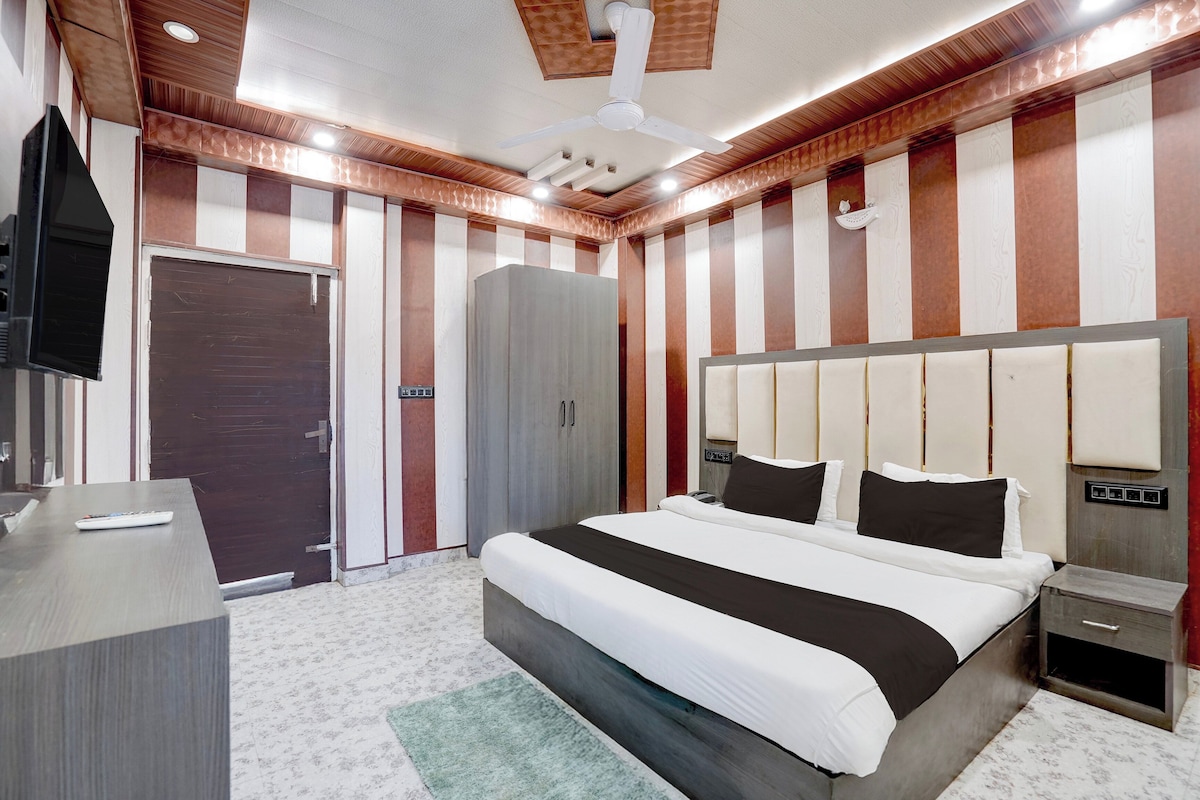 Habitación de hotel con cama, mesita de noche, televisión, armario y ventilador de techo.