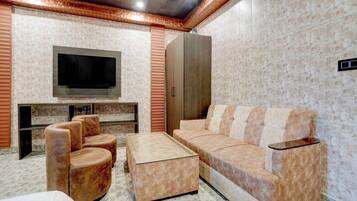 Una sala moderna con una televisión de pantalla plana, un sofá, dos sillones y una mesa de centro.