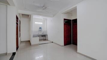 A hallway with a white ceiling, a ceiling fan, a sink with a mirror, and a red door.