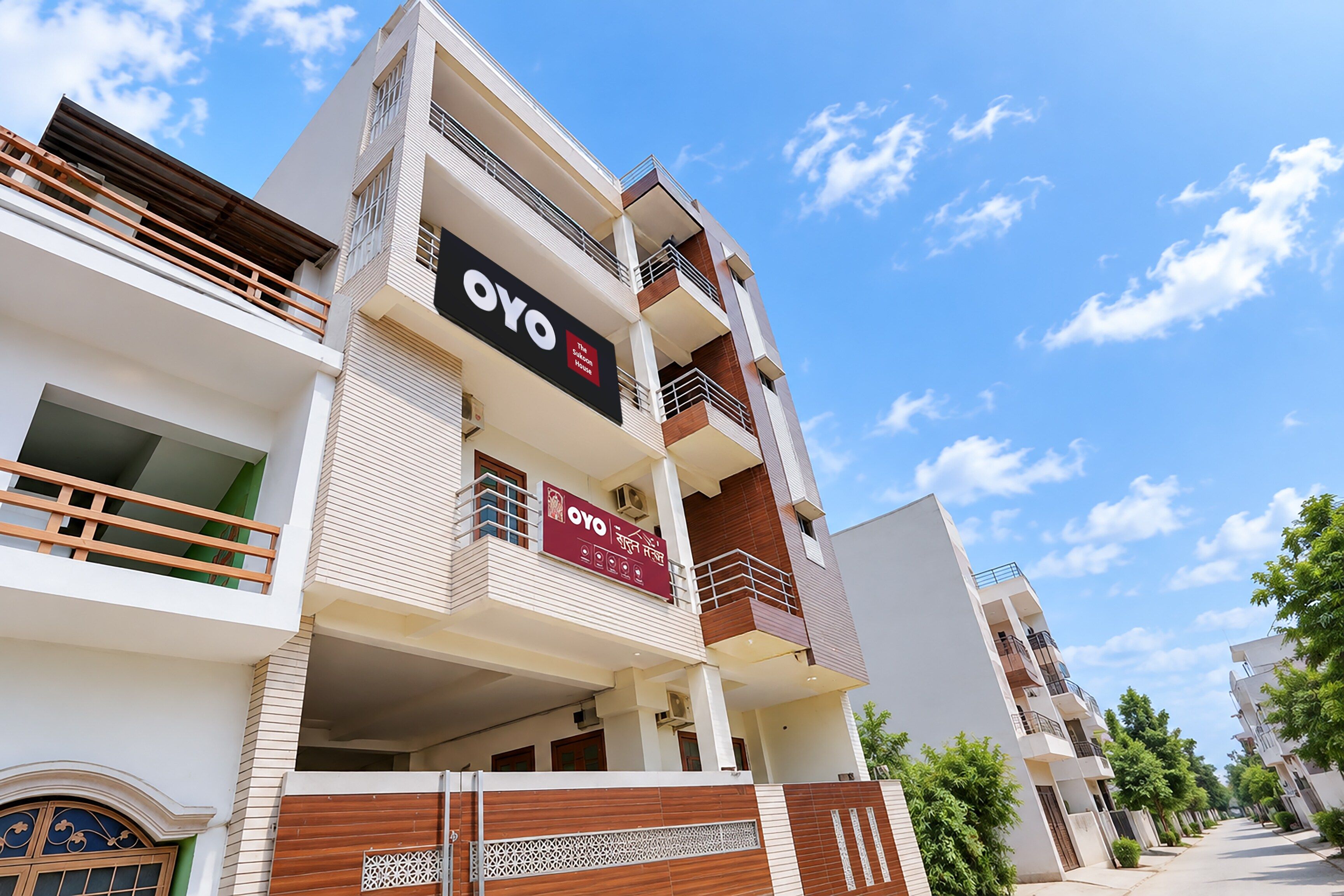 En byggnad med flera våningar, balkonger, en tydlig skylt med texten ”OYO” och en grind vid ingången.