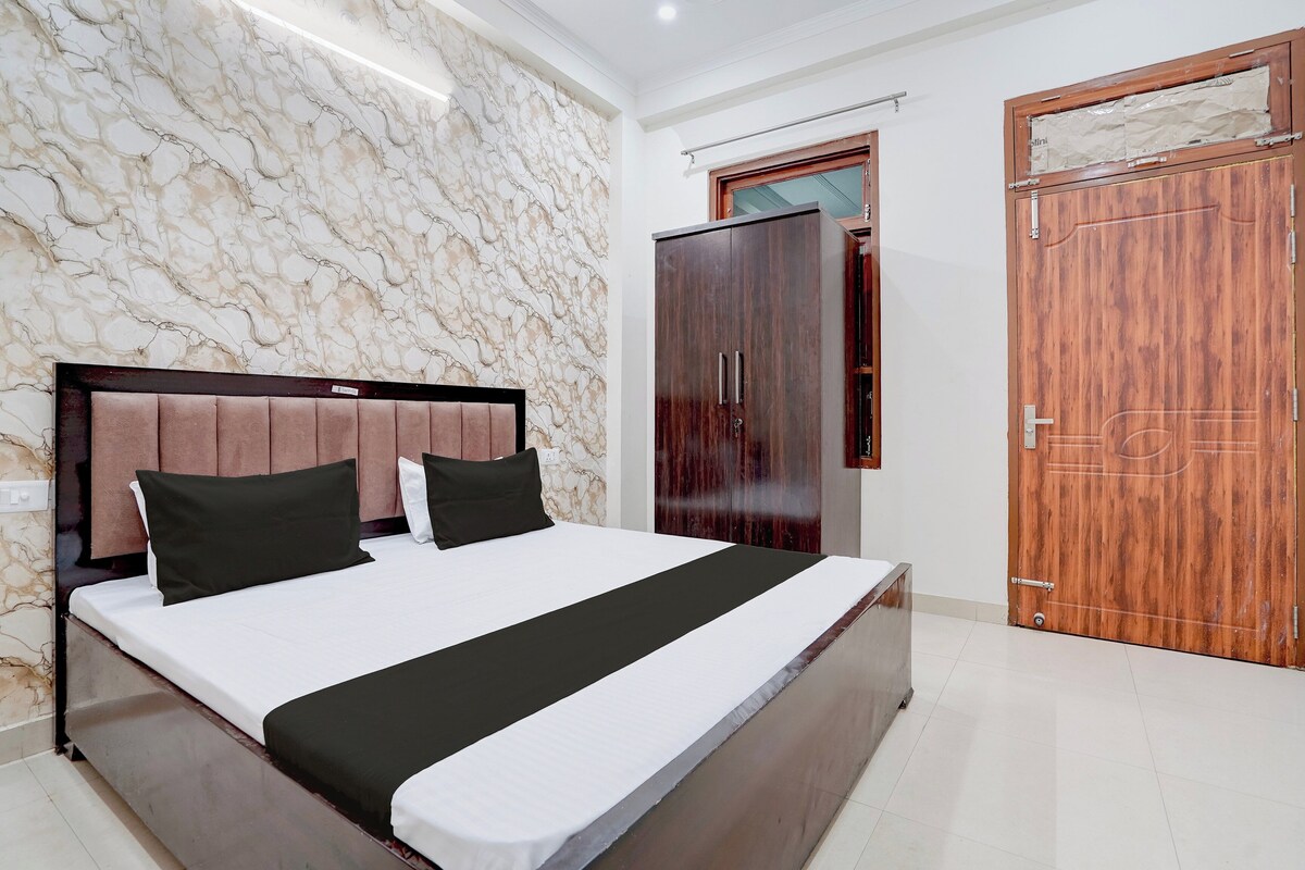 A bedroom with a marble-patterned wall, a bed with a black and white bedspread, and a wooden wardrobe.