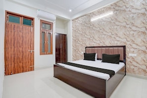 A bedroom with a bed, wooden wardrobe, and a marble-patterned wall. - Hotel O The Sukoon House (Lucknow)