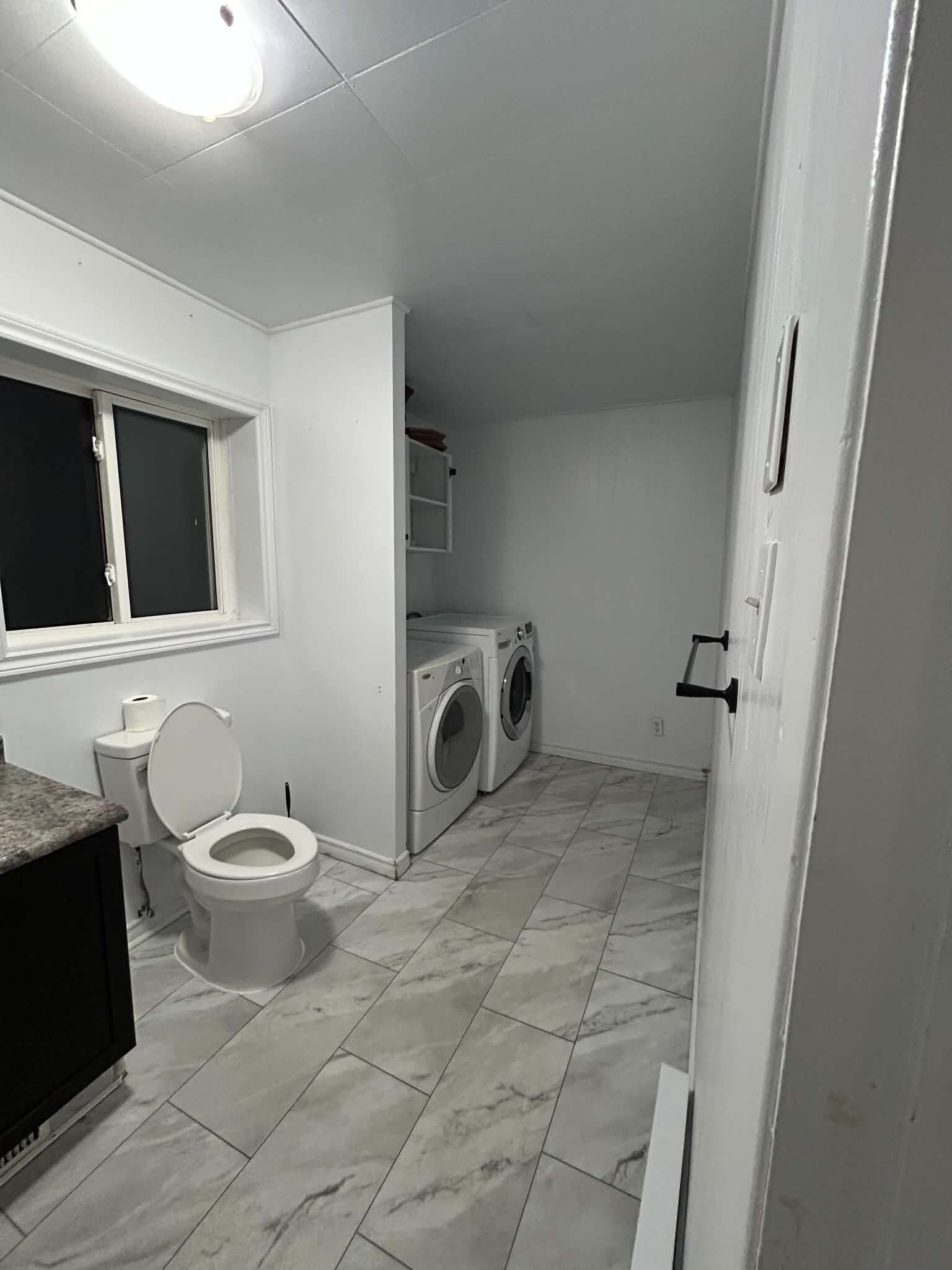 A small, clean bathroom with a toilet, sink, and washing machine.