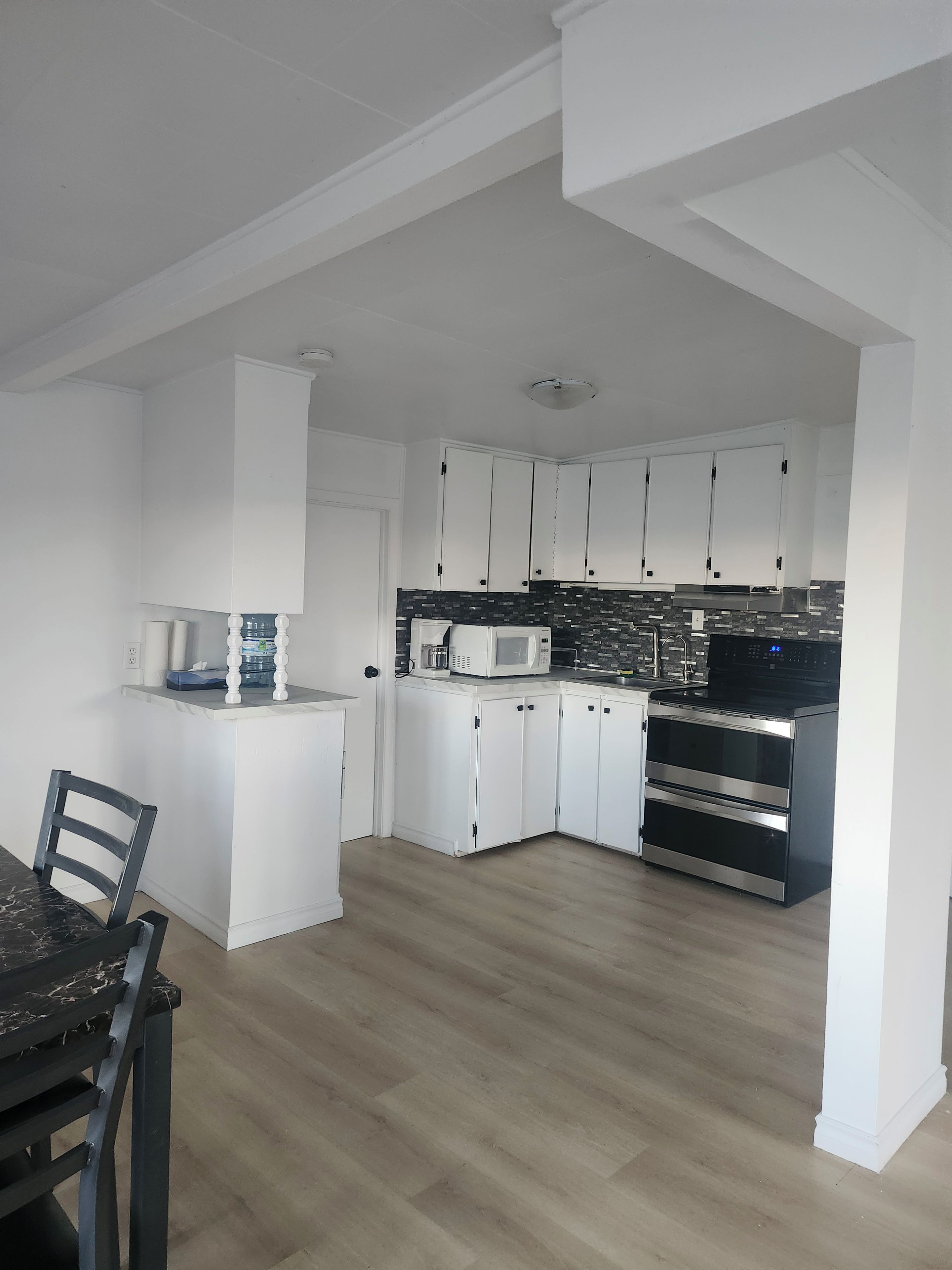 A modern kitchen with white cabinets, a microwave, and a double oven.