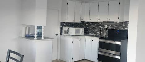 A modern kitchen with white cabinets, a microwave, and a double oven.