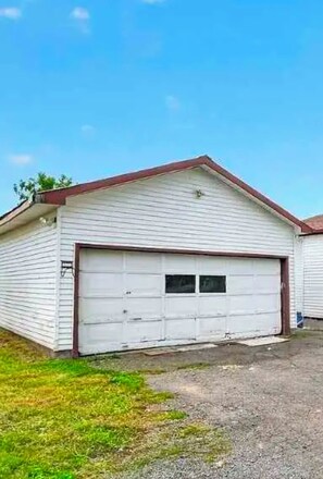 A single-story building with a white exterior and a red roof. It features a large garage with two doors.