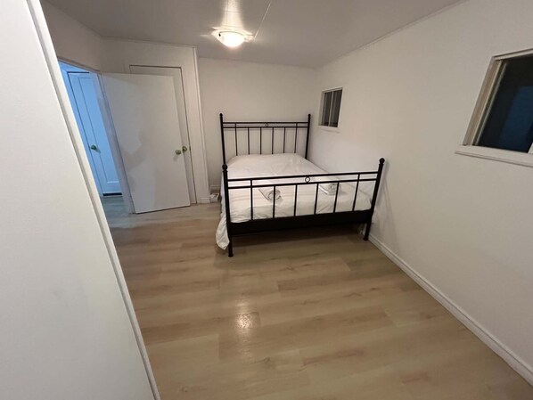 A bedroom with a single bed, a door, and a window.