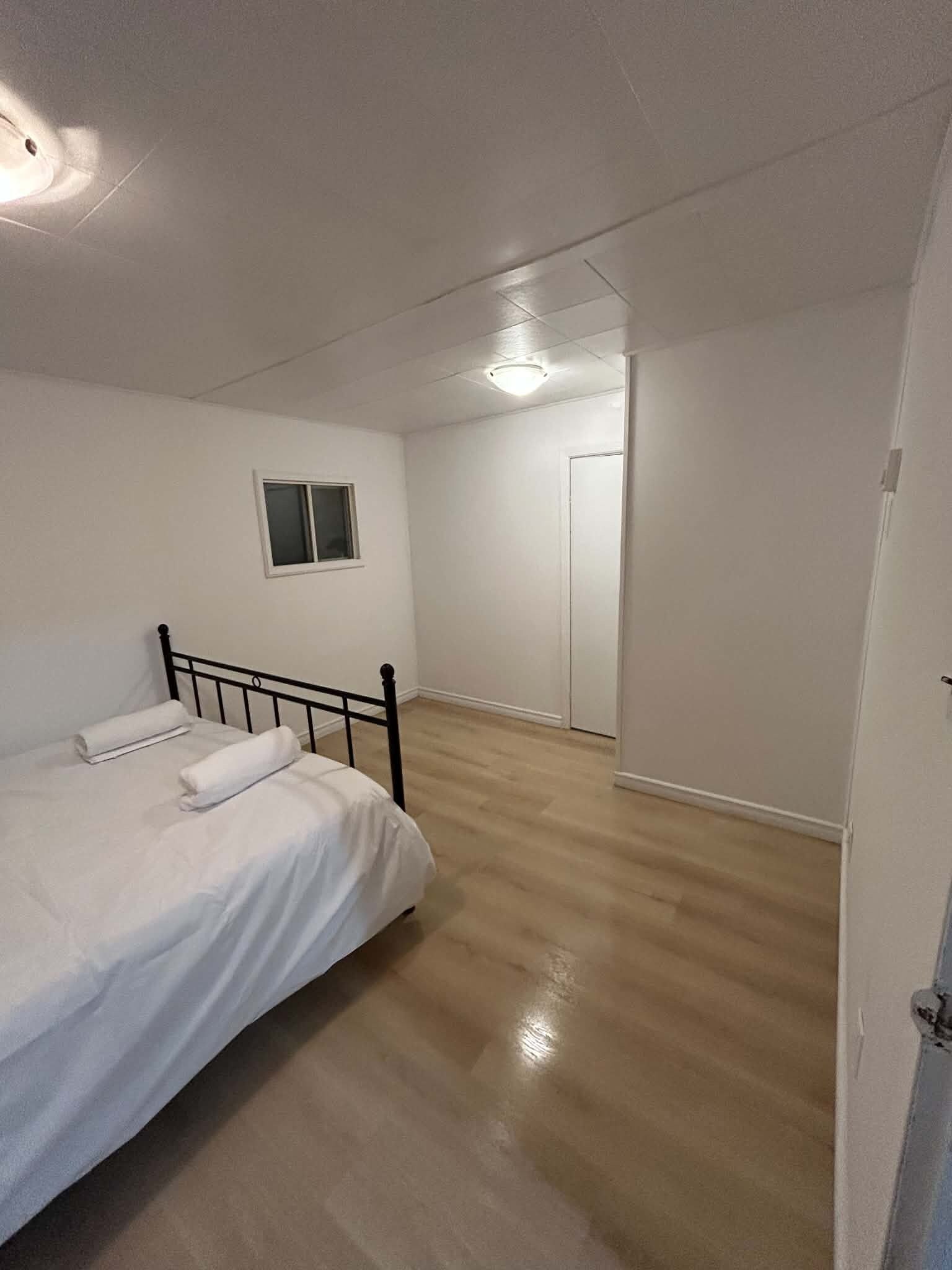 A bedroom with a bed, a window, and a door.