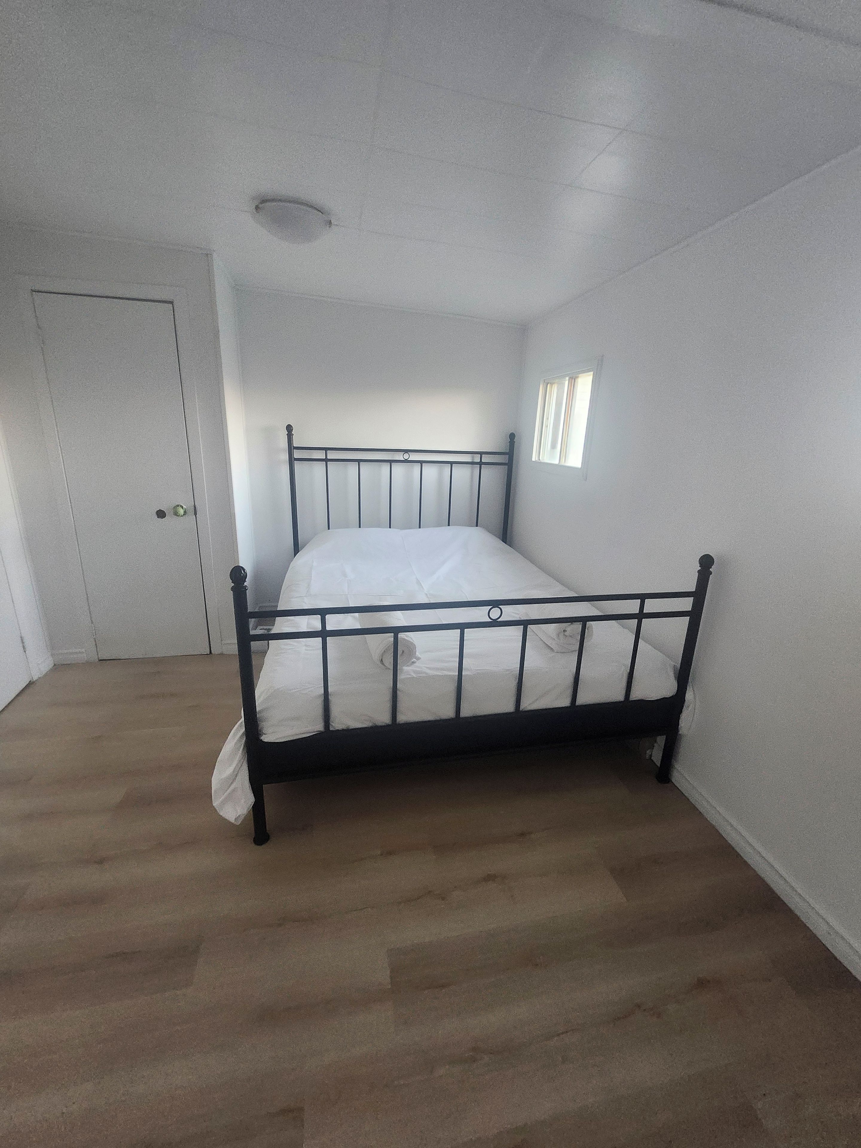 A room with a single bed, a door, and a window.