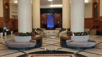 Eine Lobby mit einer Chandelüster, zwei Sofas, einem Empfangstresen und einer blau beleuchteten Wand.
