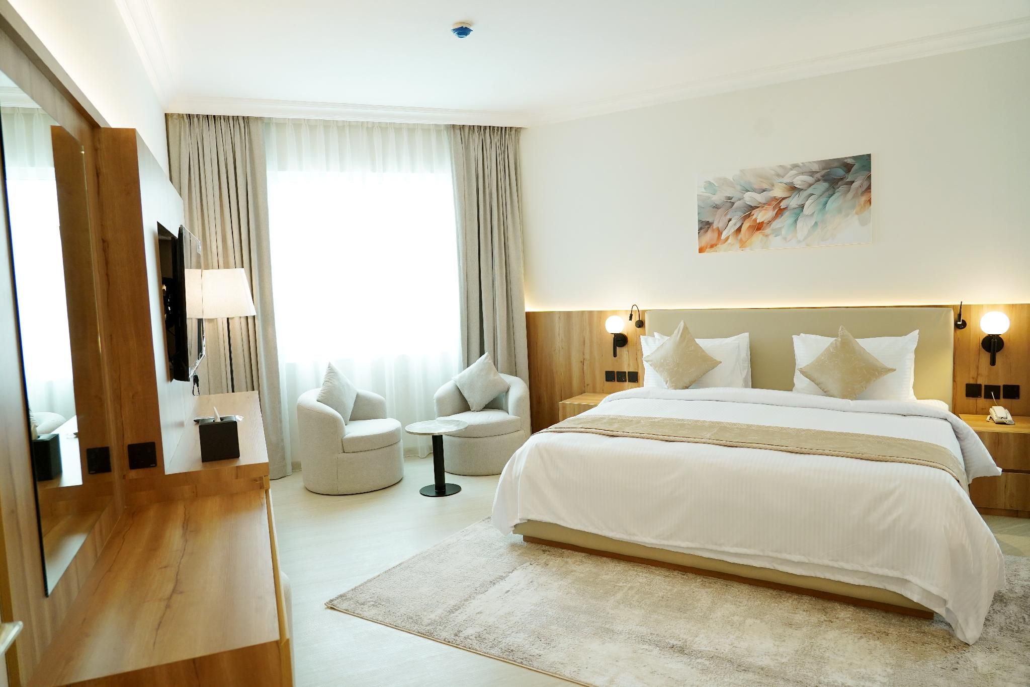 Ein Hotelzimmer mit einem großen Bett, einem Schreibtisch, einem Stuhl und einem Gemälde an der Wand.