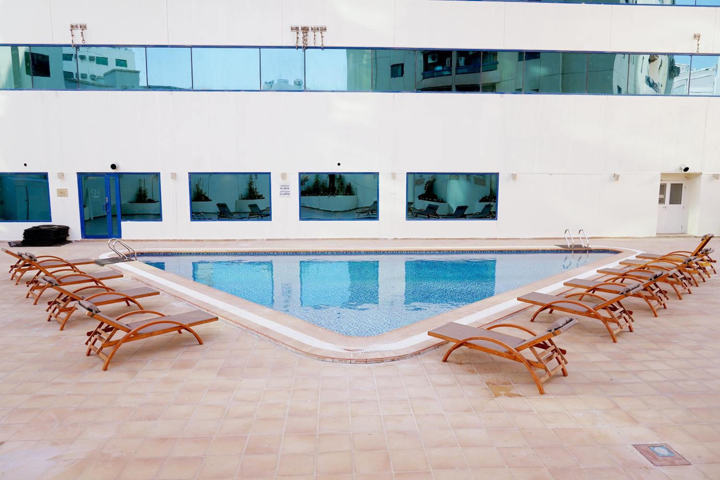 Une piscine dotée de chaises longues et offrant une vue sur la ville grâce à de grandes fenêtres.