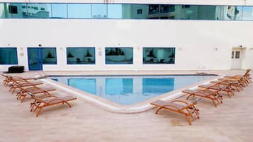 Una piscina amb gandules i vista a la ciutat a través de grans finestres.