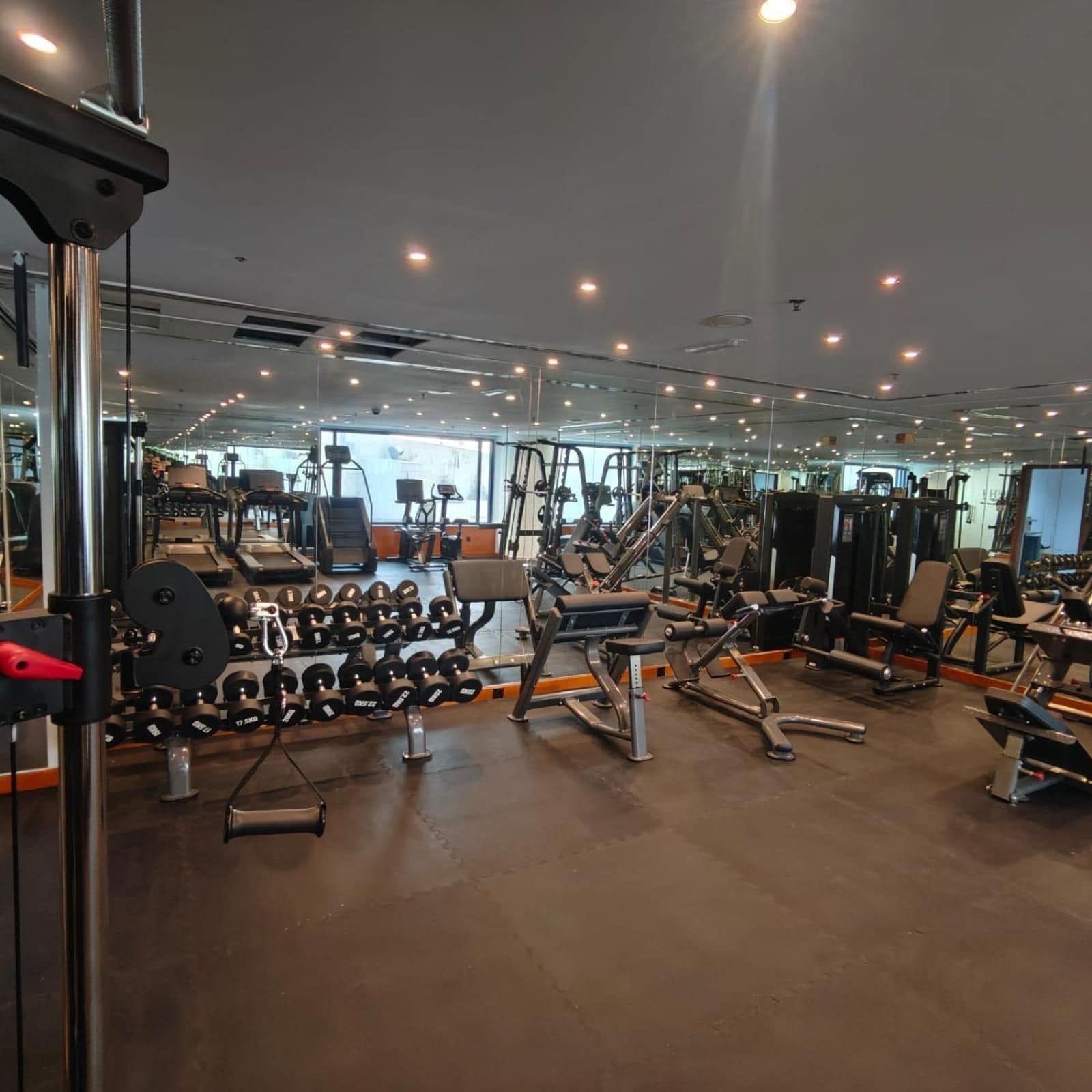 A gym with various exercise equipment, including dumbbells, benches, and weight machines.