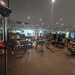 A gym with various exercise equipment, including dumbbells, benches, and weight machines. - Al Hayat Palace Hotel (Sharjah)