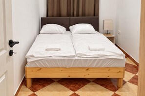 A double bed with a wooden frame, white bedding, and a nightstand with a lamp. - Your Vienna Encore 1BR near Stadthalle (Vienna)
