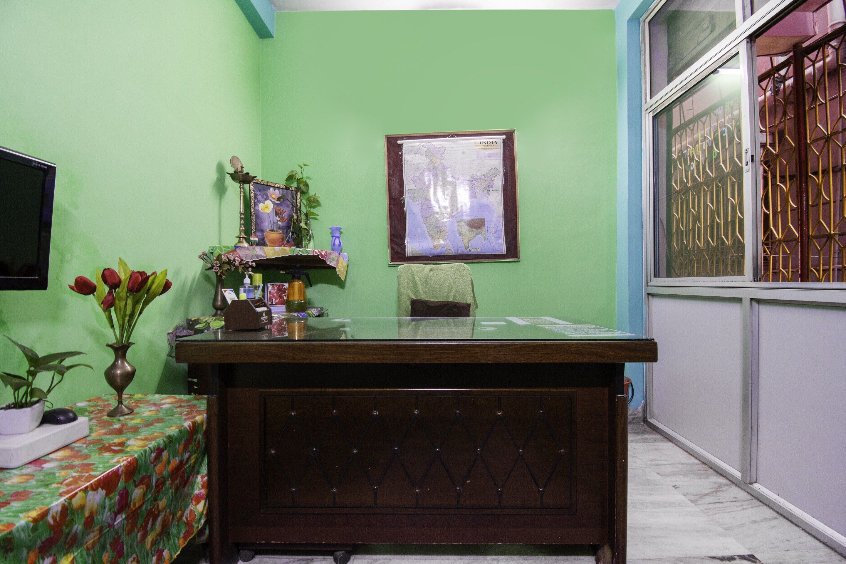 A room with a wooden desk, a map on the wall, and a window with metal bars.