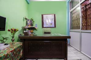 Una habitación con un escritorio de madera, un mapa en la pared y una ventana con barrotes.