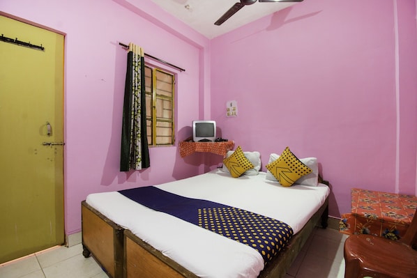 A bedroom with a bed, a television, and a small table.