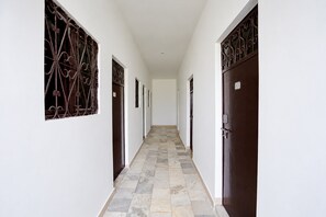 Un pasillo con suelo de baldosas y puertas a ambos lados, que conduce a habitaciones individuales.