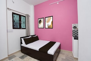 Un dormitorio con cama, ventana con cortinas y dos cuadros en la pared.