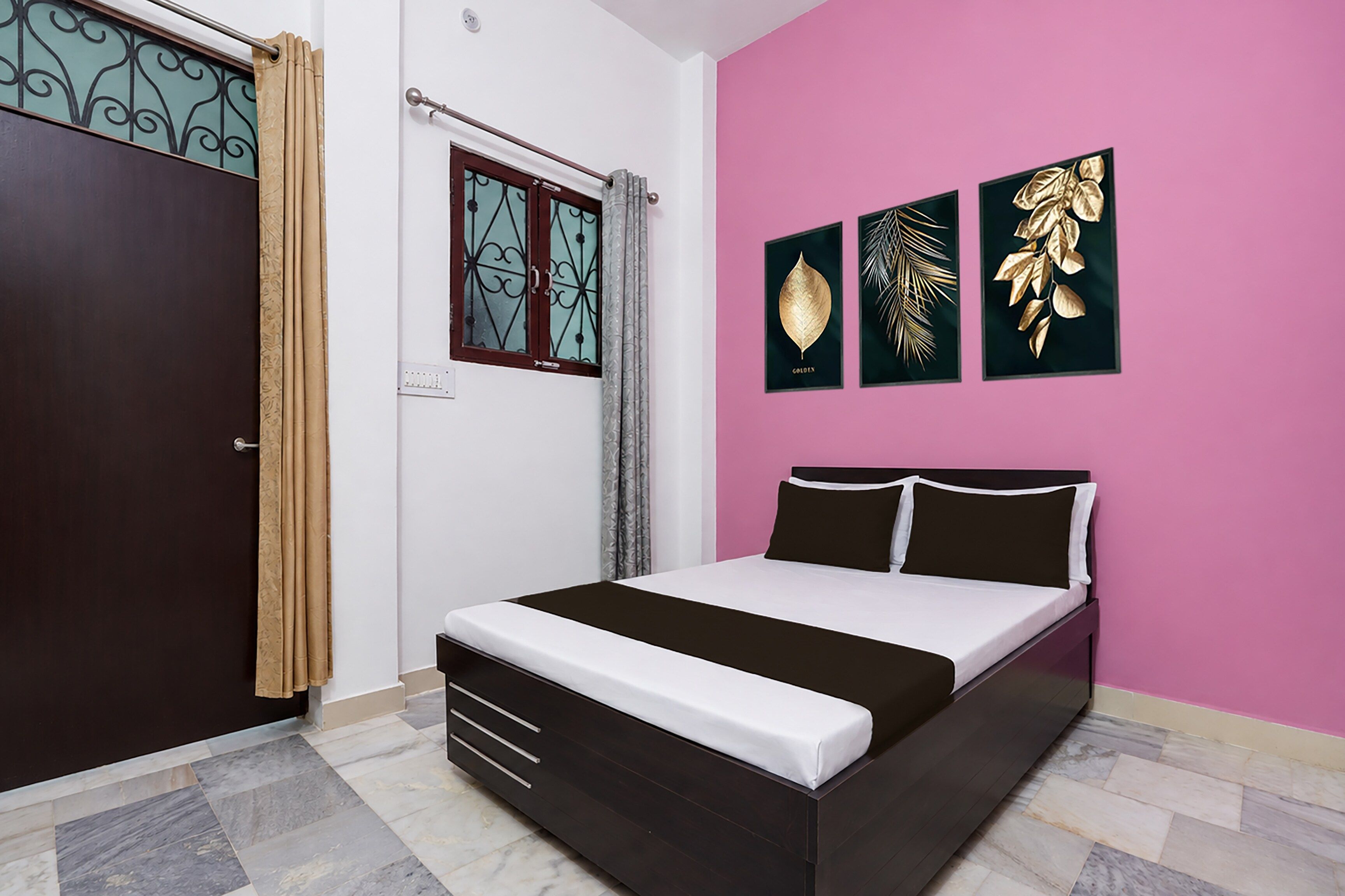 A bedroom with a bed, a wardrobe, a window with curtains, and three framed wall art pieces.
