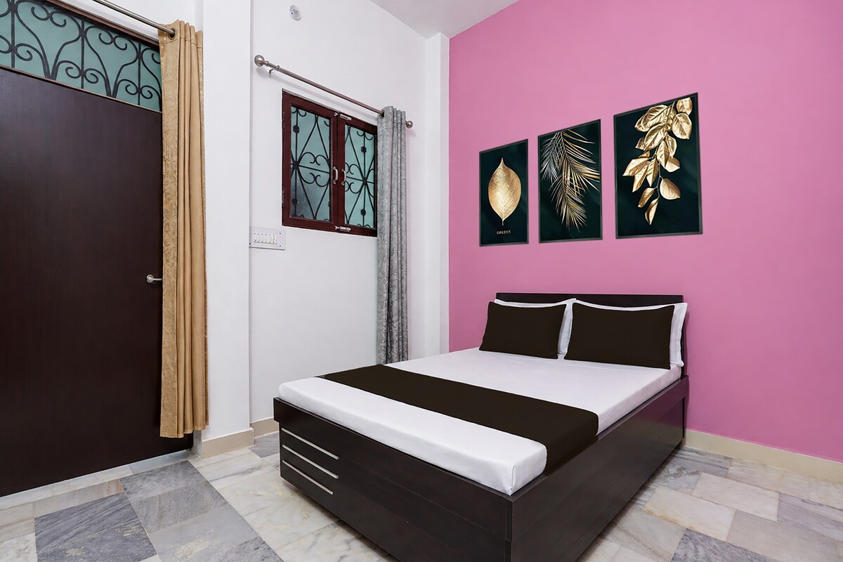 A bedroom with a bed, a wardrobe, a window with curtains, and three framed wall art pieces.