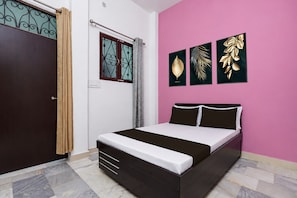 A bedroom with a bed, a wardrobe, a window with curtains, and three framed wall art pieces. - HOTEL O AAVYA INN (Lucknow)