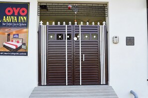 Entrada de hotel con una gran verja oscura, adornada con detalles decorativos y un letrero encima.