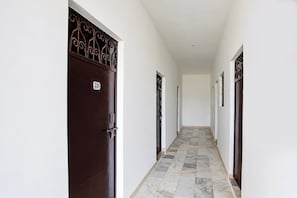 Un pasillo con una puerta marrón oscuro marcada 'SOI' y piso de baldosas.