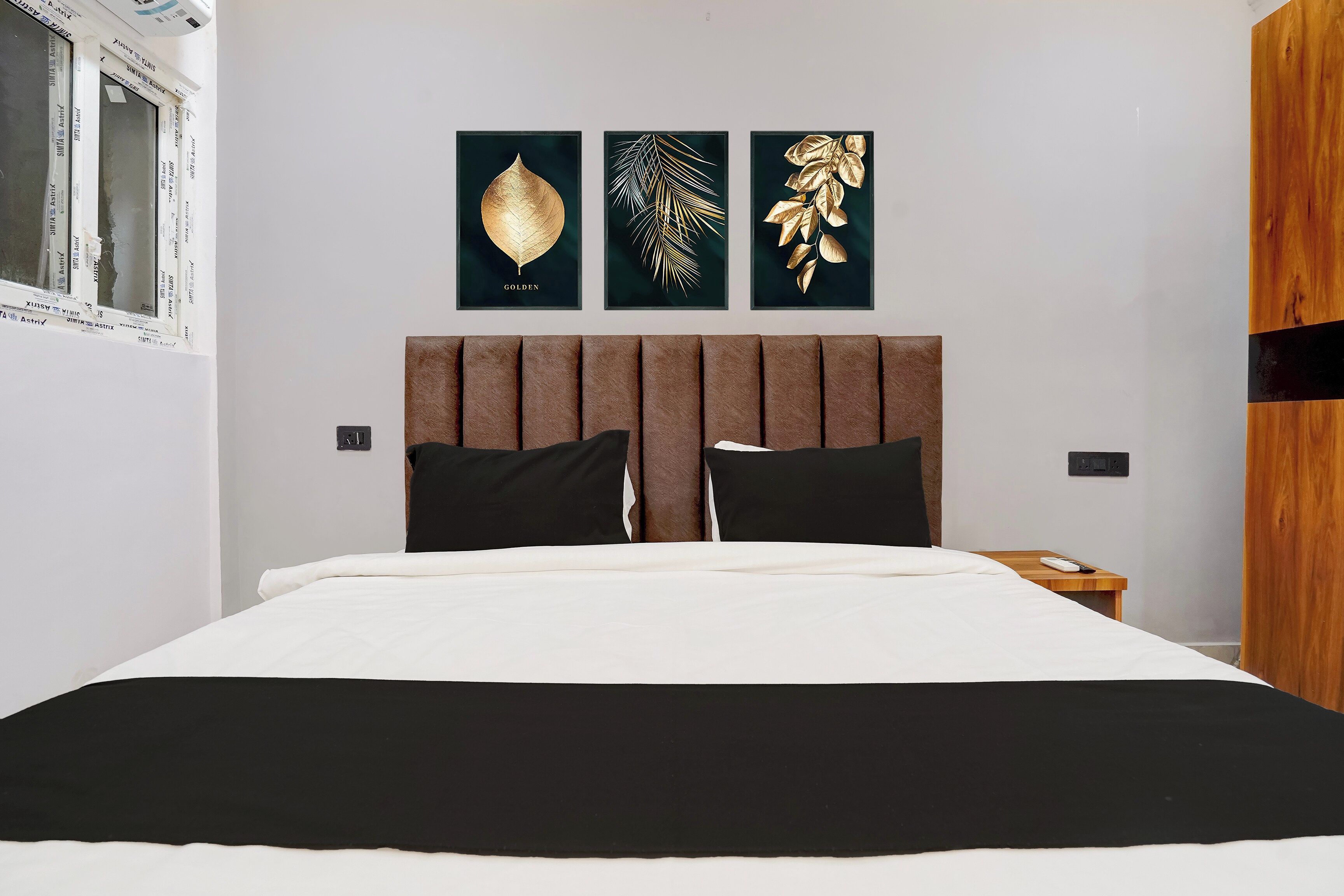 Une chambre à coucher avec un lit, une table de chevet et trois œuvres d’art encadrées accrochées au mur.
