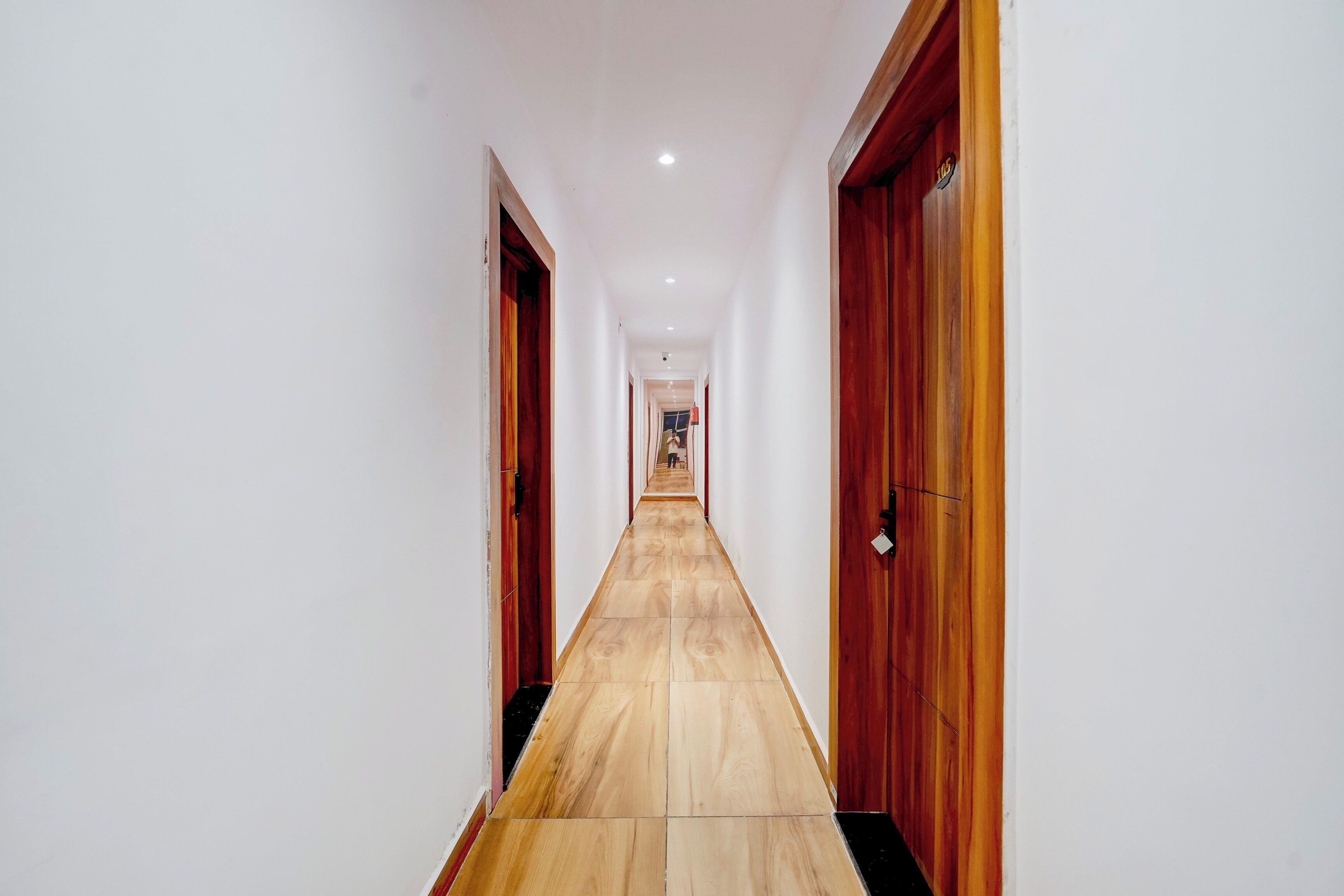 A long, narrow hallway with wooden flooring and doors on both sides.