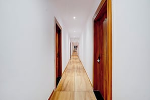 A long, narrow hallway with wooden flooring and doors on both sides. - Hotel O SS Comfort (Lucknow)