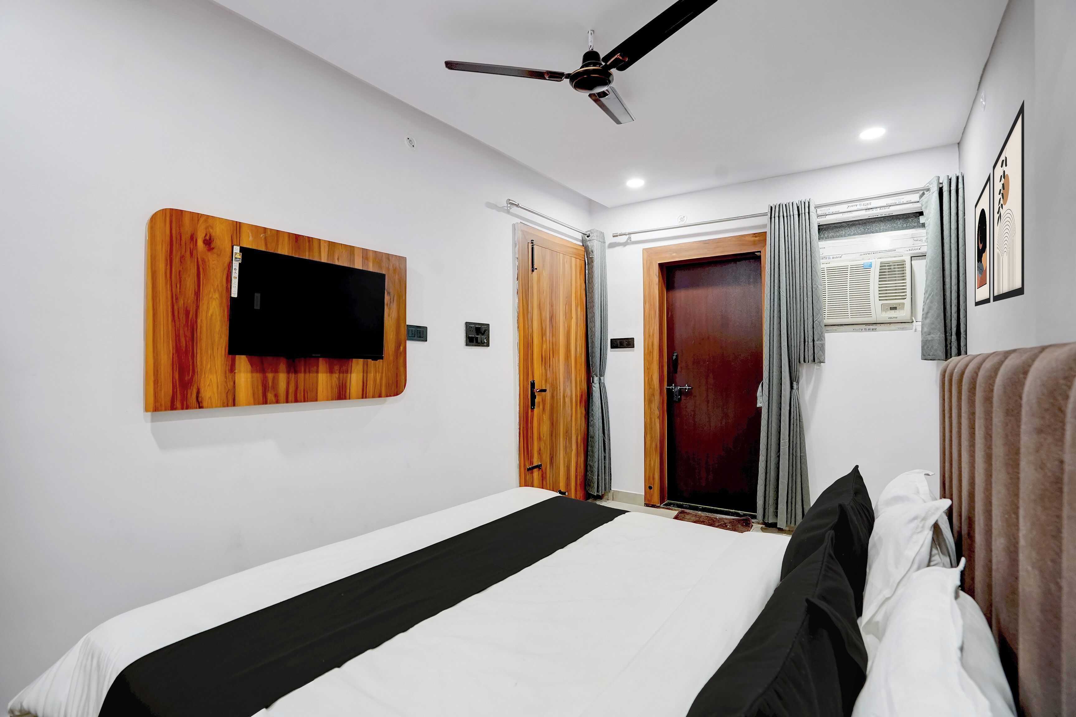 A bedroom with a bed, a ceiling fan, a mounted TV, and a wardrobe.
