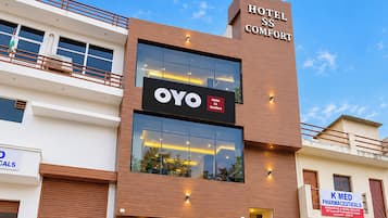 Un edificio de hotel moderno con un cartel destacado que dice 'Hotel SS Comfort' y un cartel más pequeño que dice 'OYO'.