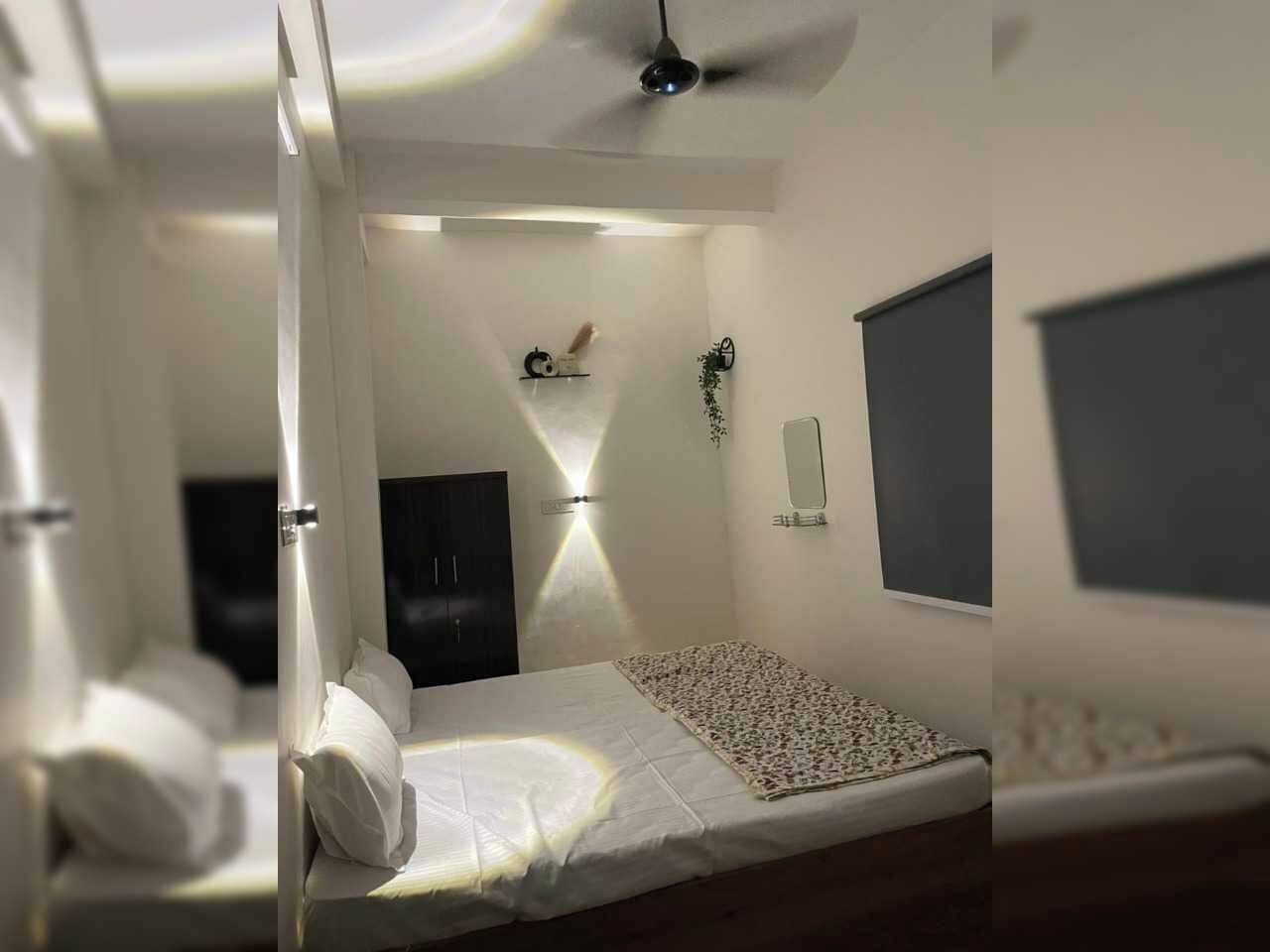 A bedroom with a bed, a bedside table, a wall-mounted TV, and a ceiling fan.