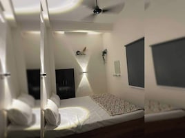 Quarto com cama, mesa de cabeceira, televisão fixada na parede e ventilador de teto.