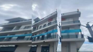 A multi-story building with balconies, a sign for 'Ovo,' and a blue awning.